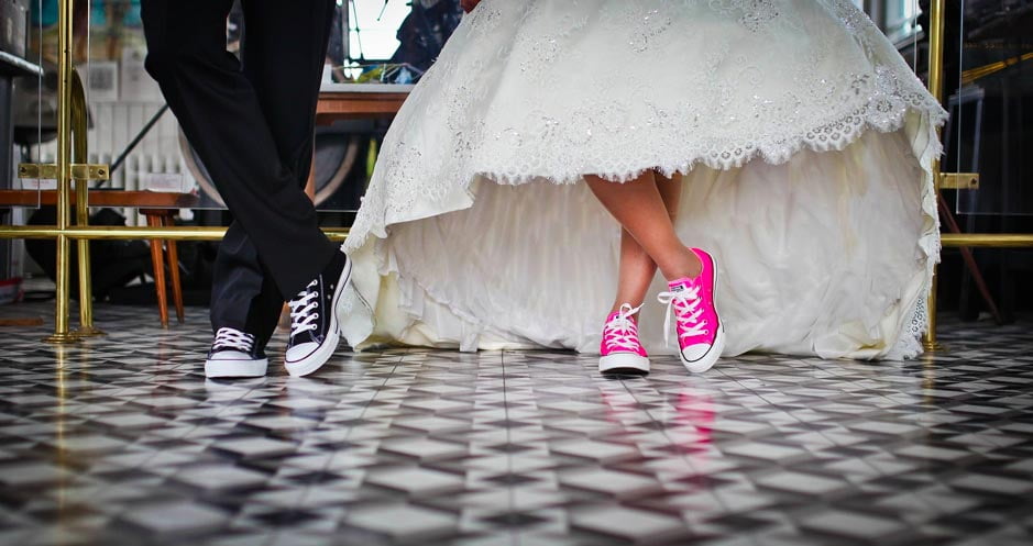 A bride wearing pink baseball shoes under her dress